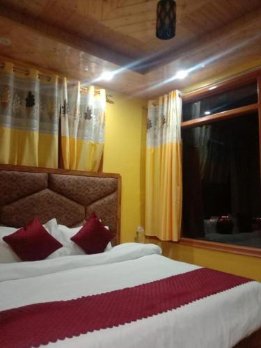 a bedroom with a bed with red pillows and a window at Kanha hotel in Shimla
