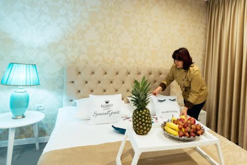 a woman standing next to a bed with a tray of fruit at Pensiunea Mira in Bîrlad