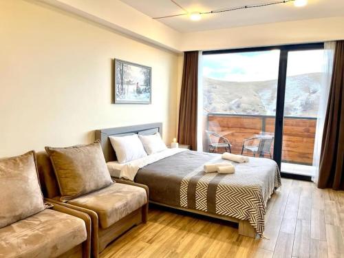 a bedroom with a bed and a couch and a window at New Gudauri Redco, Twins, Near Gondola in Gudauri