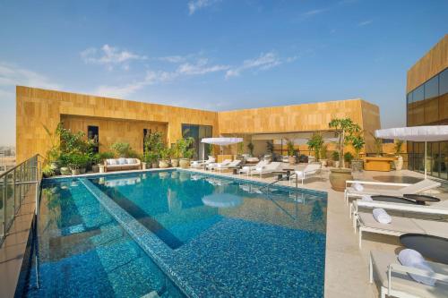 einen Pool mit Stühlen und ein Gebäude in der Unterkunft The St. Regis Riyadh in Riad