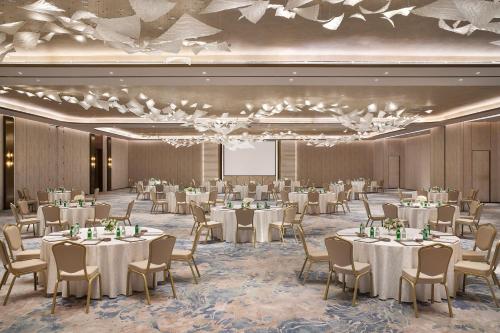 einen Bankettsaal mit weißen Tischen und Stühlen und einem Bildschirm in der Unterkunft The St. Regis Riyadh in Riad