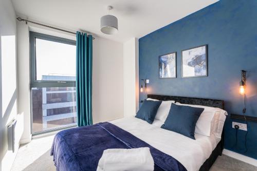 um quarto com uma cama grande e uma parede azul em Morden 2 Bed Apartment - Manchester Old Trafford em Manchester