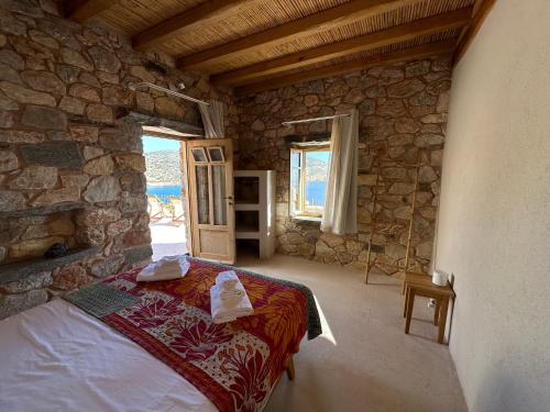 um quarto com uma cama numa parede de pedra em Phisis Nature Retreat em Donoussa