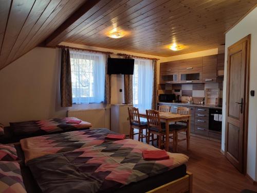 a bedroom with two beds and a table and a kitchen at Ubytování Niki in Rokytnice nad Jizerou