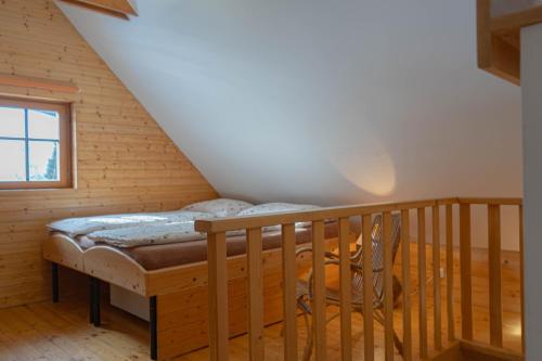 a bed in a wooden room with a staircase at Chalupa Na Sklepě in Velké Karlovice