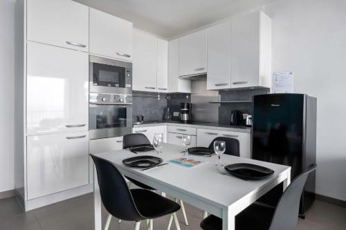 - une cuisine blanche avec une table blanche et des appareils noirs dans l'établissement Un séjour ou un week-end face mer à la Baule, à La Baule