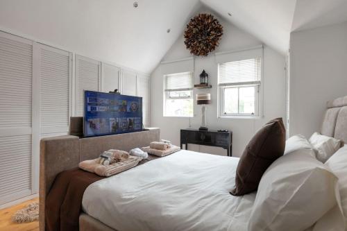 - une chambre avec un grand lit, des murs blancs et des fenêtres dans l'établissement Dovehouse, à Londres