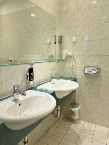 a bathroom with two sinks and a mirror at Sure Hotel by Best Western Wilhelmshaven City in Wilhelmshaven