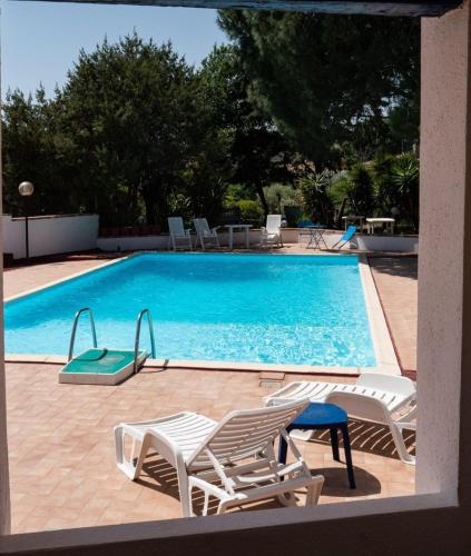 a swimming pool with two lawn chairs and avisorvisor at Hotel Sa Lolla in Barùmini