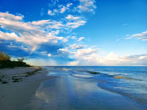 a view of the beach with a rainbow in the sky at Watamu Beach Cottages in Watamu