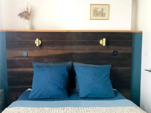 a bed with blue pillows and a wooden headboard at La bohème place aux herbes in Uzès