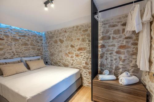a bedroom with a bed and a stone wall at Efrosini Apartments in Heraklio