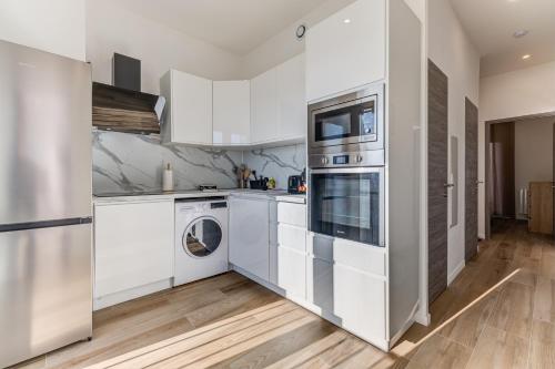 une cuisine avec des armoires blanches et une laveuse et une sécheuse dans l'établissement Les Grands Cèdres - Wifi, AC, Parking, à Nice
