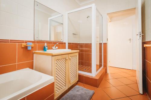 a bathroom with a tub and a sink and a shower at Beachfront property, Victoria Bay, Garden route in Victoria Bay