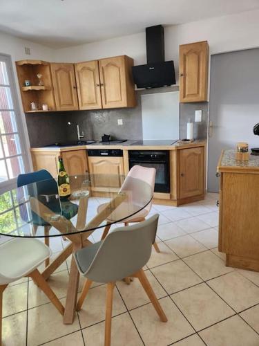 une cuisine avec une table en verre et des chaises. dans l'établissement Maison cosy et décorée avec goût à la campagne, à Sévérac