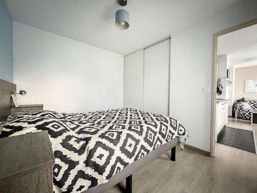 a bedroom with a black and white comforter on a bed at Appartement le peuplier proche de la plage. in Bray-Dunes