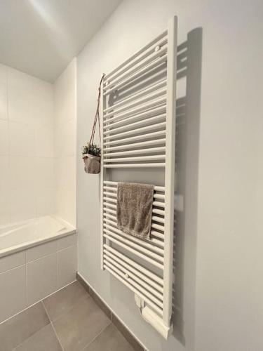 a white bathroom with a towel rack and a tub at Appartement le peuplier proche de la plage. in Bray-Dunes