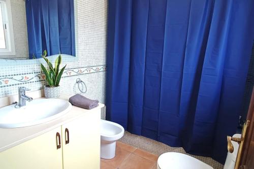 y baño con cortina de ducha azul y aseo. en Torre Roda Vistas al Mar, en Roda de Bará