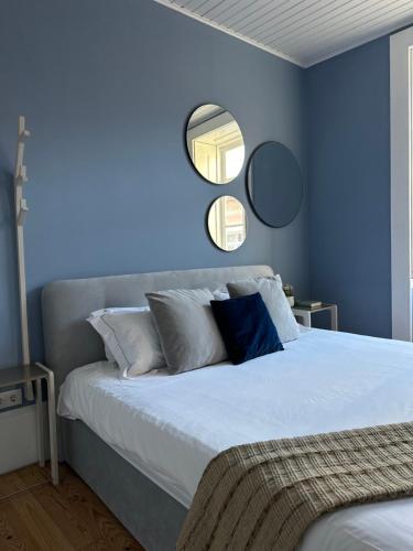 a blue bedroom with a bed with two mirrors on the wall at Aveiro History Apartments in Aveiro