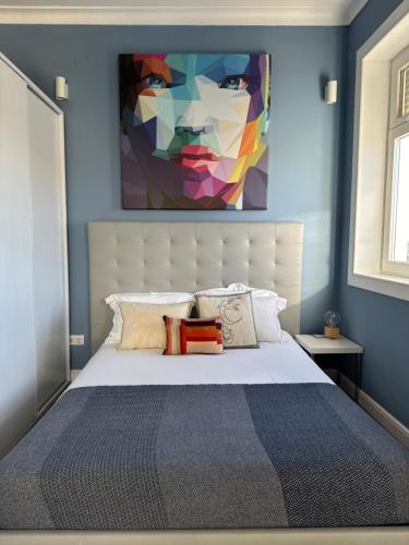 a bedroom with a bed with a painting on the wall at Aveiro History Apartments in Aveiro
