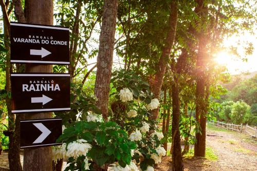a sign for a trail in a forest with flowers at Pousada Cavaleiro dos Pireneus in Pirenópolis