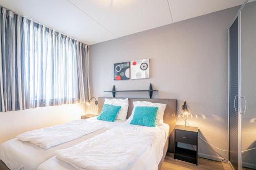 een slaapkamer met een groot bed met blauwe kussens bij Appartementencomplex Juliana 46 in De Koog