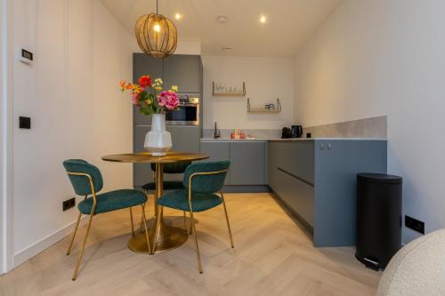 a kitchen with a table and chairs and a vase with flowers at Welcome in - Luxe vakantiewoningen nabij strand ZEEBRIES - Dishoek in Koudekerke