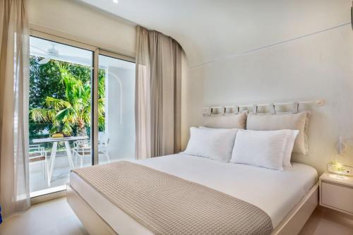 a white bedroom with a bed and a balcony at Cocoοns Luxury Suites & Villas in Fourka