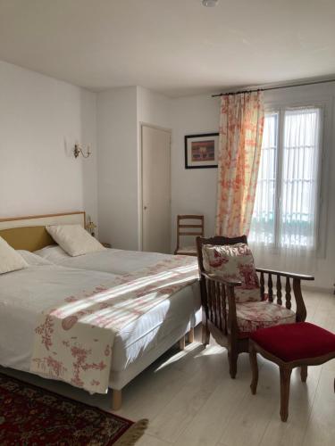 Un dormitorio con una cama y una silla y una ventana. en Le Grand Paris, en Digne-les-Bains