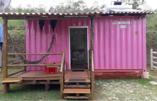 uma cabana cor-de-rosa com um alpendre e um baloiço em Pousada Recanto dos Bentos em Itapeva