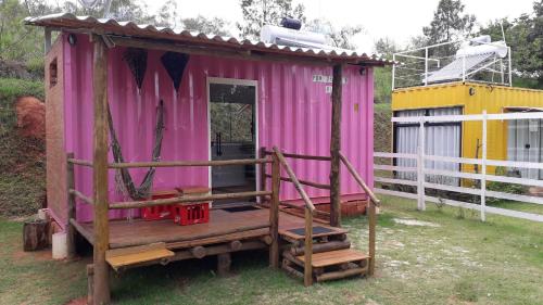 a pink shed with a porch in a yard at Pousada Recanto dos Bentos in Itapeva