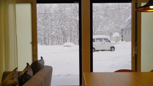 a view of a snow covered yard through a sliding glass door at Niseko White Villas1 in Niseko