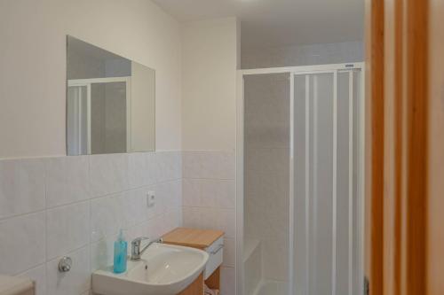 a white bathroom with a sink and a shower at Chalupa Na Sklepě in Velké Karlovice