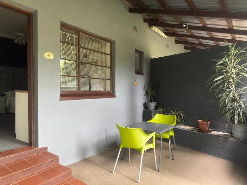 a table and two yellow chairs next to a building at Busa House in White River