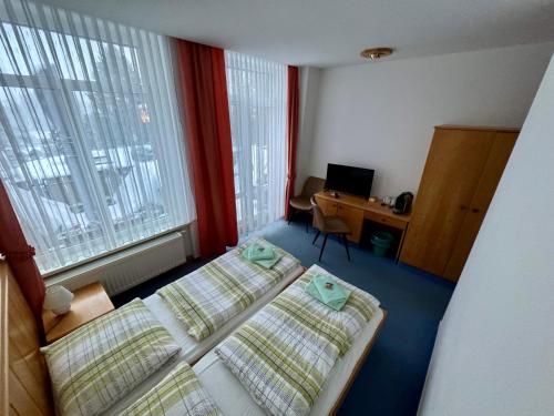 a hotel room with two beds and a desk and a window at Pension und Berggasthaus Kapellenstein in Geyer