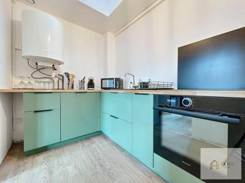 - une cuisine avec des armoires bleues et un four noir dans l'établissement Appartement place Turenne, à Dunkerque