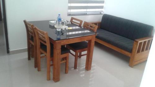 a dining room with a table and a couch at Alite Enclaves Fully furnished apartments in Trichūr