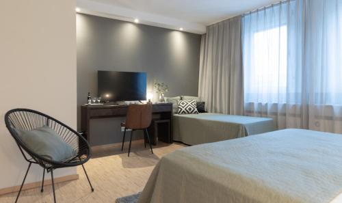 Habitación de hotel con cama, escritorio y TV. en Paragon Apartments en Frankfurt
