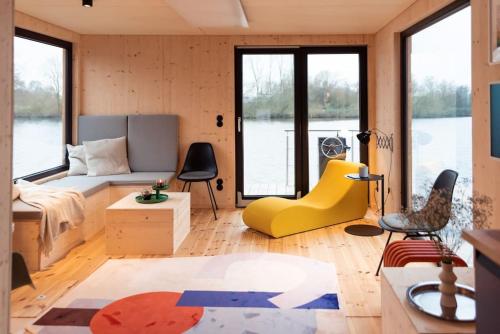 a living room with a bed and a yellow chair at Hausboot OFF im Diamantgraben an der Elbe in Hamburg