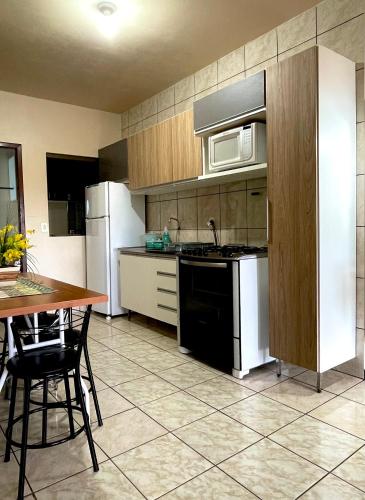 a kitchen with a stove and a microwave and a table at Apartamento aconchegante no centro de Toledo in Toledo