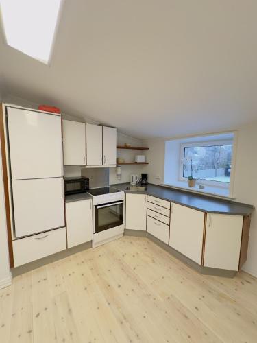 a kitchen with white cabinets and a black counter top at aday - Holiday Apartment in the heart of Frederikshavn in Frederikshavn