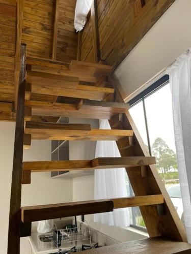 a wooden staircase in a room with a window at Pousada Portal Dos Campos in Ponta Grossa