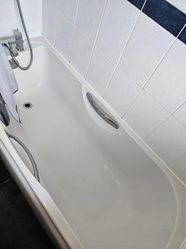 La salle de bains est pourvue d'une douche et de carrelage blanc. dans l'établissement Comfortable single room in Family home, Heathrow airport, à Northolt