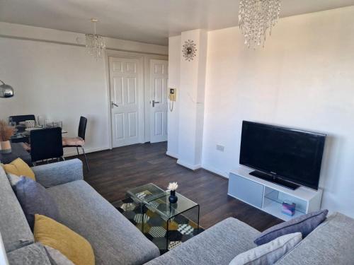 a living room with a couch and a flat screen tv at 1-Bedroom Flat Close to Manchester Airport in Handforth