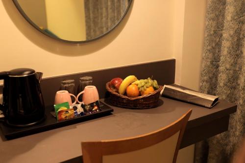 a table with a basket of fruit and a mirror at Hotel The Excellency in Surat