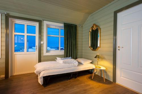 a bedroom with a bed and two windows and a door at West-End Apartment in Andenes