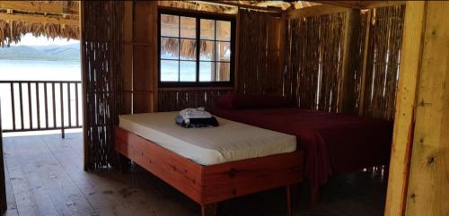 a bedroom with a bed and a window in a cabin at Cabañas sobre el mar en San Blas Narasgandub. in Nusatupo