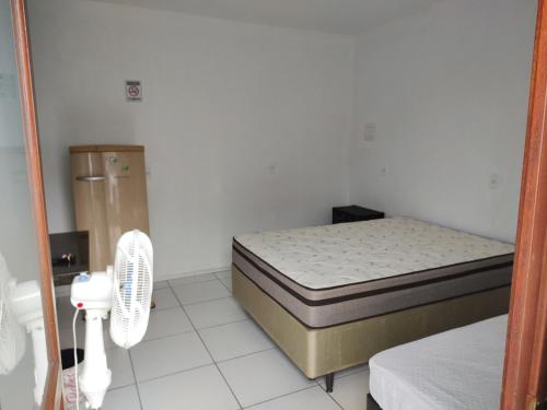 een kleine slaapkamer met een bed en een ventilator bij Hostel Pousada Casa da Praia in Passo de Torres