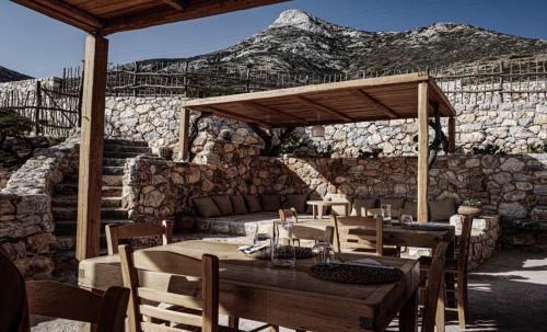 un patio con mesa, sillas y pared de piedra. en Phisis Nature Retreat, en Donoussa