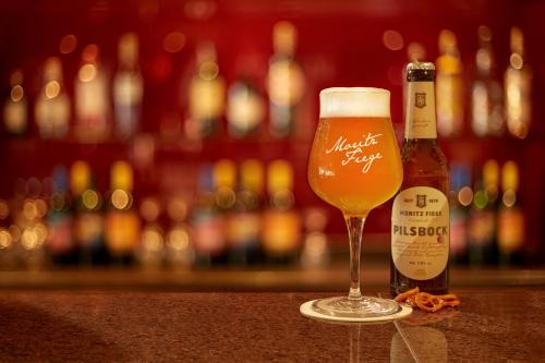 a glass of beer sitting next to a bottle of beer at H+ Hotel Bochum in Bochum